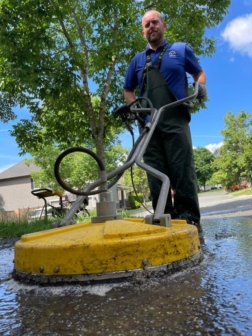 Modern office interior featuring large windows, strategic greenery, open workspace, and a seating area with a couch, stylish furniture, and a minimalist design.
